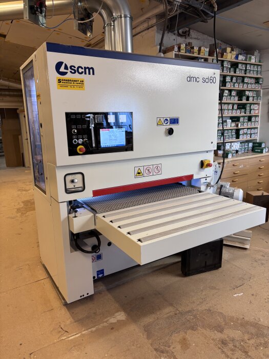 SCM bredbandsputs dmc sd60 i verkstad med rörinstallationer och hyllor i bakgrunden.