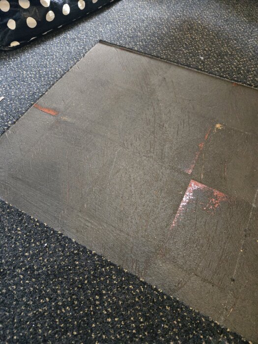 Golv med avlägsnad limmad matta visar underliggande plattor; mattrester och starkt lim på golvet. Behöver tips för skonsam borttagning av limmet.