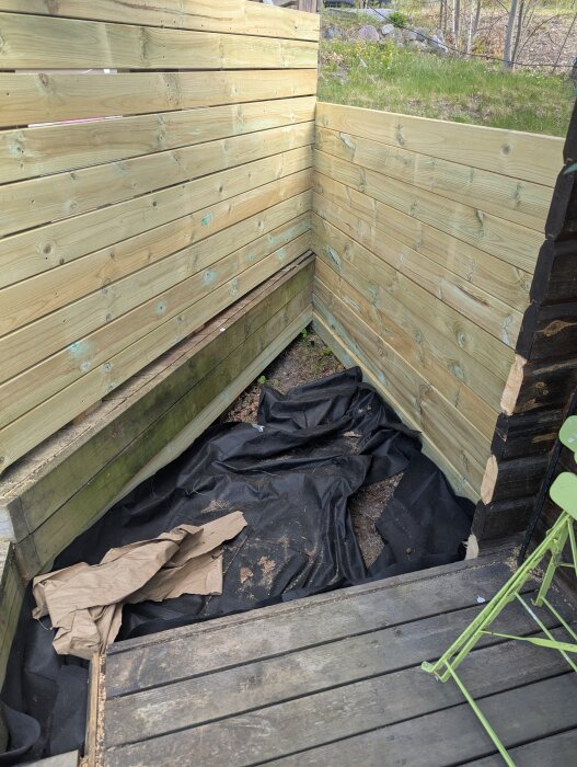 Tryckimpregnerad avgränsning med markväv i hörn, del av utekök; diskussion om att göra växthus här och jorderosion.