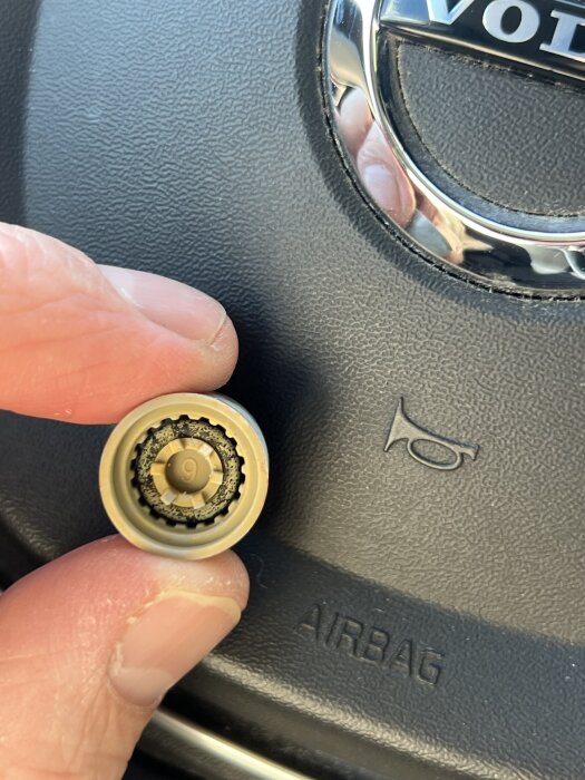 Hand håller en duschflödesbegränsare intill en bilratt.