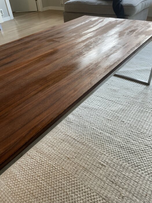 Massivt bord i valnöt med oljeglidningar på ytan, eventuellt övermättat, står på en ljus matta i ett rum.