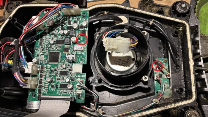 Elektronikkretskort med två upplysta lampor markerade i en robot, visar interna komponenter och anslutningar.