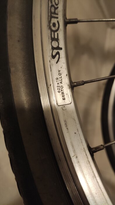 Cykeldäckets fälg med texten "SPECTRA" och märkning "622 x 19 ETRTO ALLOY", samt en ventil vid sidan av.