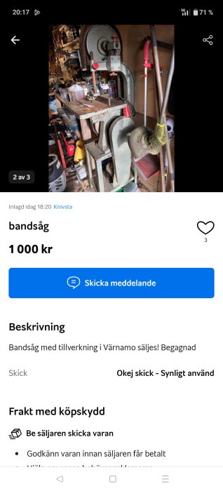 Begagnad bandsåg i ett verkstadssammanhang, omgiven av verktyg och utrustning. Bandsågen är grå med röda detaljer.
