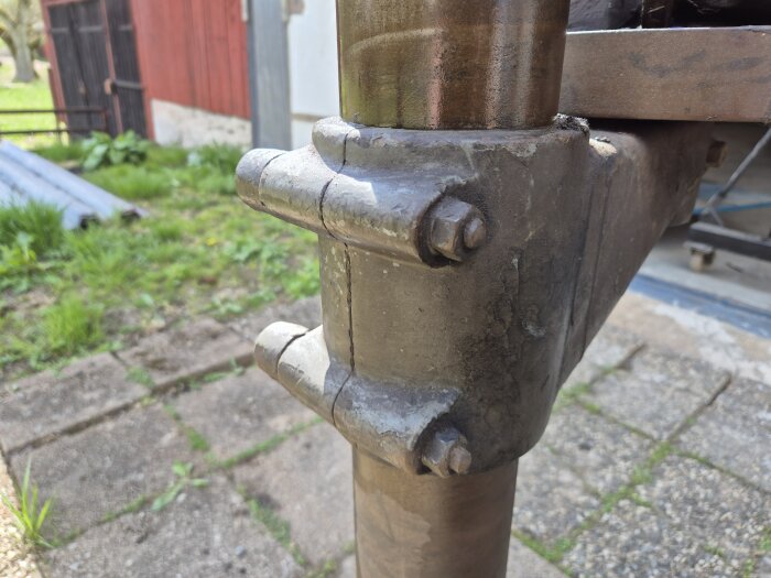 Närbild av mekanisk koppling med fyra bultar på en metallstruktur utomhus, del av diskussion om kugghjul och byggprojekt.