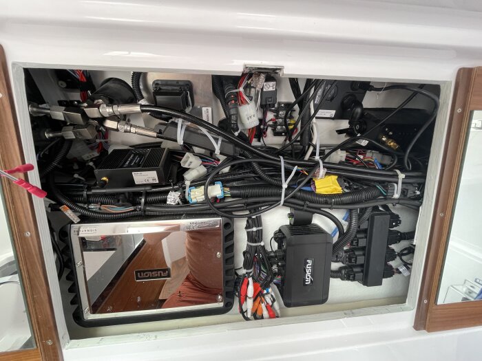 Bild av en båtens motorrum med en mängd kablar och elektronikmoduler, däribland en identifierbar modul markerad "Fusion".