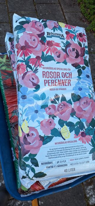 En säck naturgödslad specialjord för rosor och perenner från Rölunda med blom- och fjärilsmotiv.