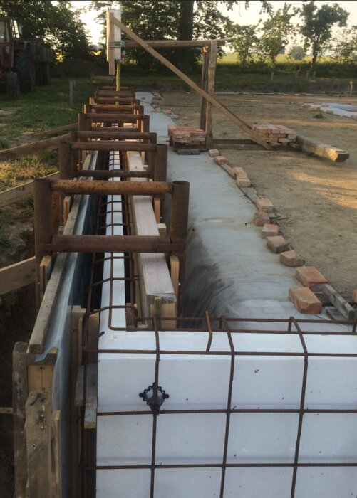 Form för gjutning av grundmur med 15mm plywood och 45x95 reglar, förstärkt med hemmagjorda byglar, cirka 1,25m hög. Omgiven av tegelstenar.