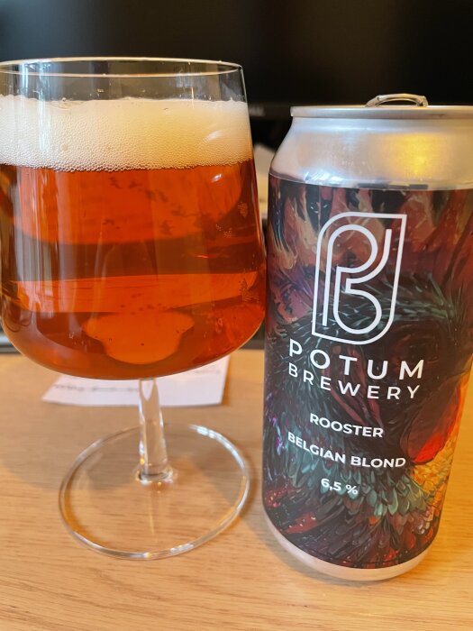 En ölburk med etiketten "Potum Brewery Rooster Belgian Blond" och ett glas fyllt med bärnstensfärgad öl på ett bord.