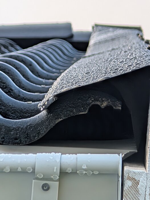 Tegelpannor med kapad kant och bred plåt, ej avslutande i dalens topp, ses från sidan.