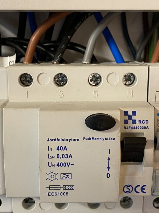 En jordfelsbrytare med flera anslutna kablar visas, märkt med specifikationer som 40A, 0,03A, 400V och fått CE-certifiering.