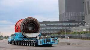 Ett stort cylinderformat objekt transporteras på en blå plattform vid Barsebäck kärnkraftsverk.