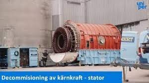 Kärnkraftsanläggning under uppbyggnad med en stor, röd-orange stator och maskineri; text på bild antyder avveckling av kärnkraft - stator.