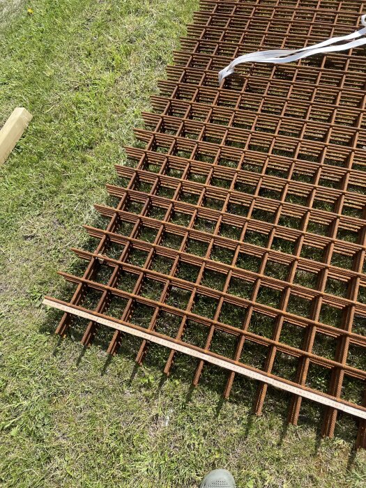 Armeringsjärn ligger på en gräsmatta, redo för byggprojekt.