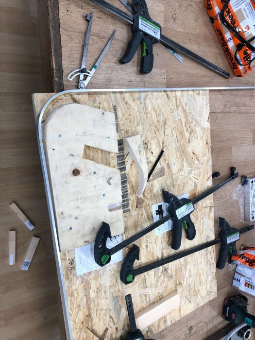 Jigg för bockning av aluminiumramar med tvingar och verktyg på en arbetsbänk.
