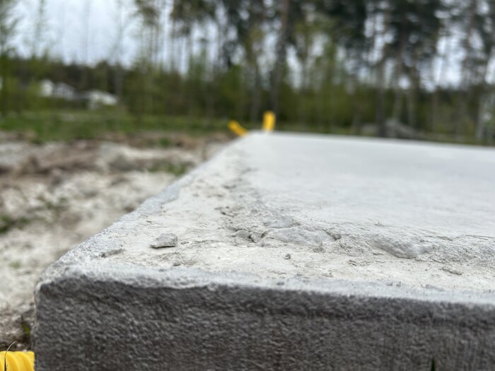 Närbild på betongplatta utomhus, med ojämn yta och sprickor, som ska användas för uterum med pelare enligt ritningar.