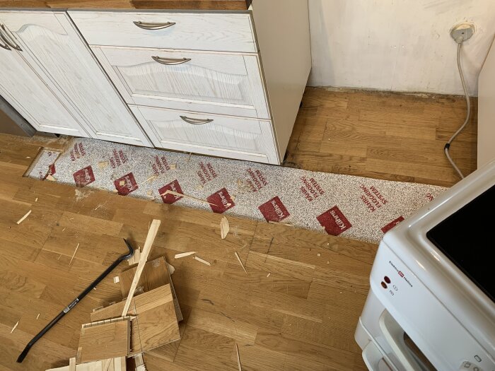 Rivet trägolv, synliga lager och verktyg i köket inför installation av induktionsspis. Förbereder ytan för en ny Viking-spismodell.