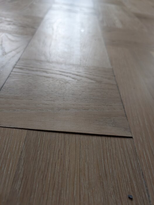 Parkettgolv med en del som har lyfts och blivit ojämn efter slipning.
