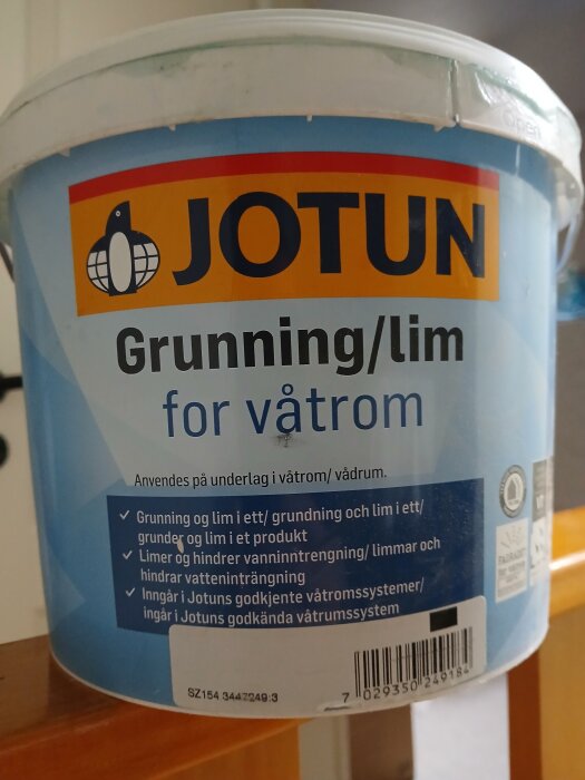 En burk med Jotuns våtrumslim, beskrivet som grunder och lim i ett, för användning på underlag i våtrum och vådrum.