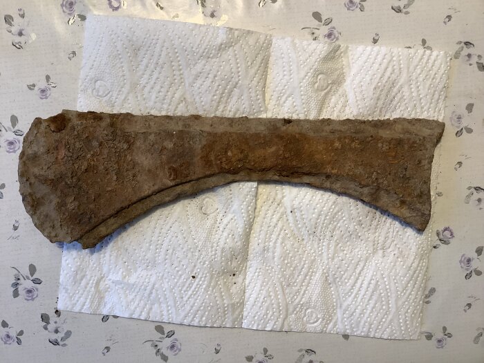 Rostig, gammal yxhuvud ligger på papper.