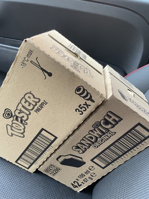 Kartonger med glassmärkena "Tofster" och "Sandwich" i en bil.