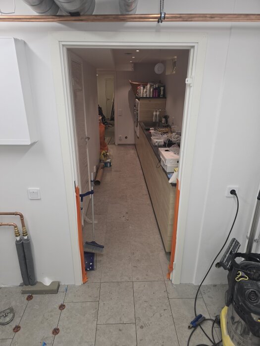 Vy av ett halvfärdigt duschrum med nylagd klinkers, verktyg och material synliga. En del av listen saknar fortfarande färg.