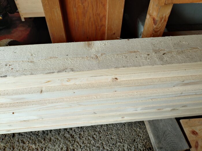 Brädor för dörrfoder, där några är släta och andra ohyvlade, ligger staplade.