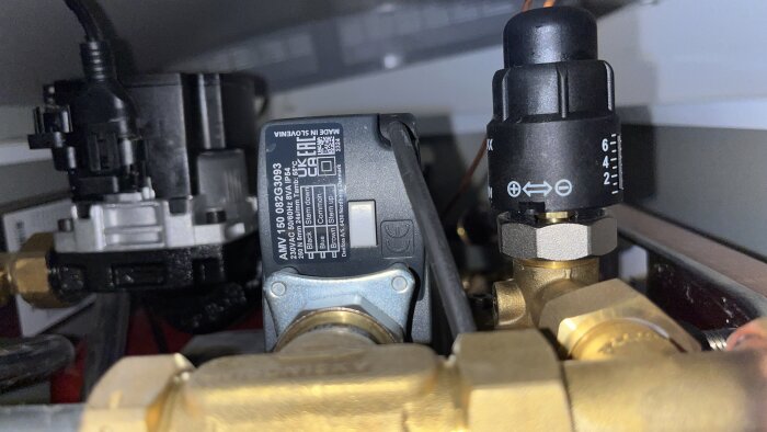 Närbild av en justeringsventil och kopplingar i ett rörsystem, med en etikett påknuten komponent i fokus.