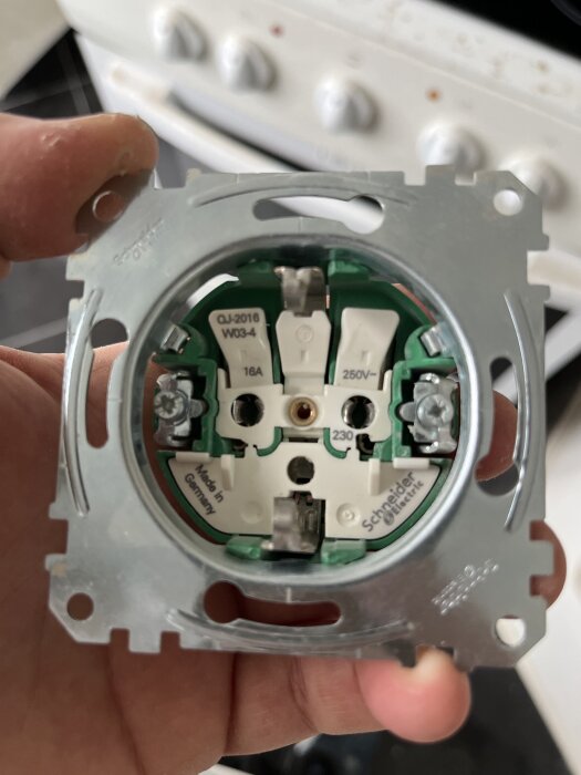 Bild på ett vägguttag med jordanslutning i mitten, används i en diskussion om placering av neutral och ledare.