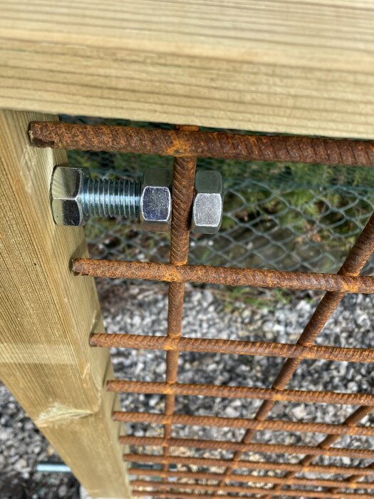 Rostigt metallgaller fastsatt med bultar på en träram.