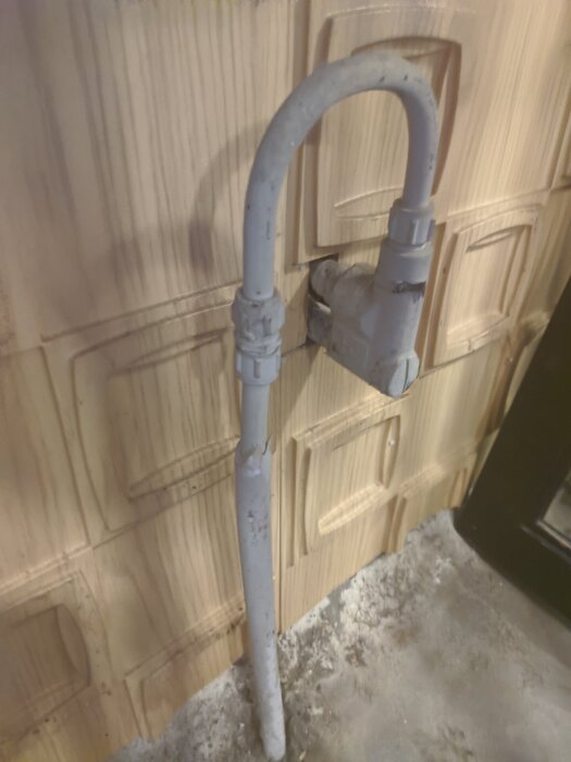 Vattenutkastare i garage kopplat med böjt rör, visar ineffektiv tätning och behov av byte.