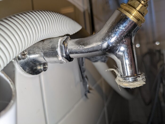 Kromad vattenventil med fastsittande ventilöverstycke, omgiven av vit flexslang, behöver identifieras för byte.