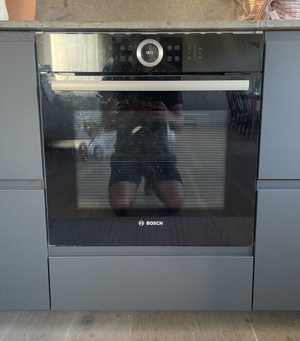 Ugn installerad mellan skåp med synligt glapp till bänkskiva ovan, exponerande metallprofilen på skåpsstommen.