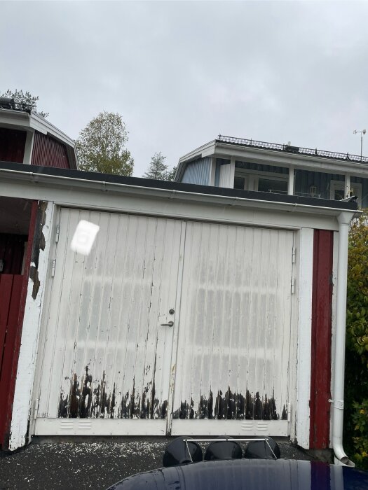 Sliten vit slagport med flagande färg, röd och vit vägg, behov av renovering.