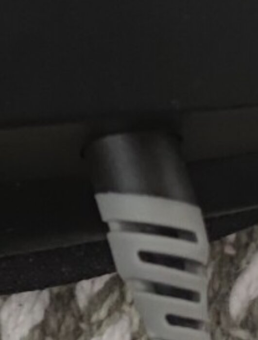 Närbild av övergången mellan en sladd och en enhet, med fokus på en löstagbar kontakt eller koppling.