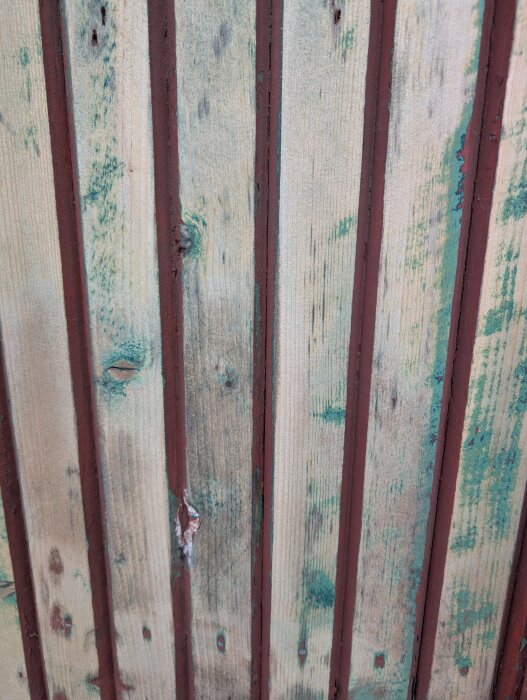 Krackelerad falu rödfärg på träpanel med grön färg under.