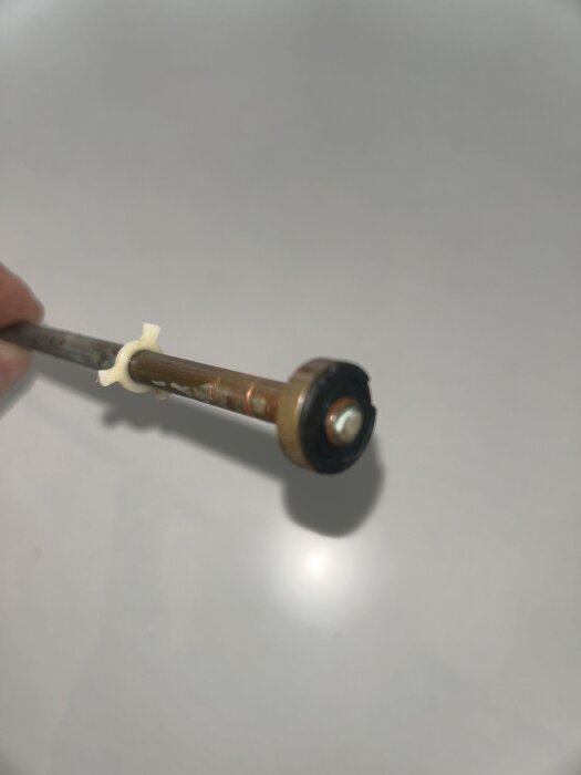 En metallstav med en skadad packning i ena änden, använd i en stallets kran.