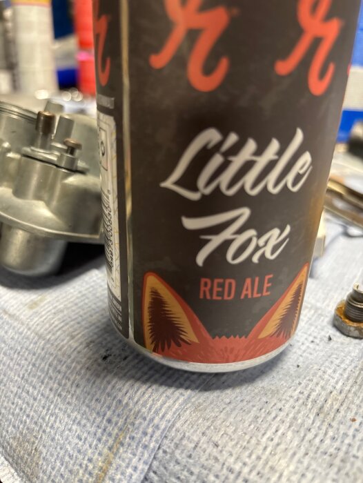 Burk med Little Fox Red Ale öl på arbetsbänk i ett garage.