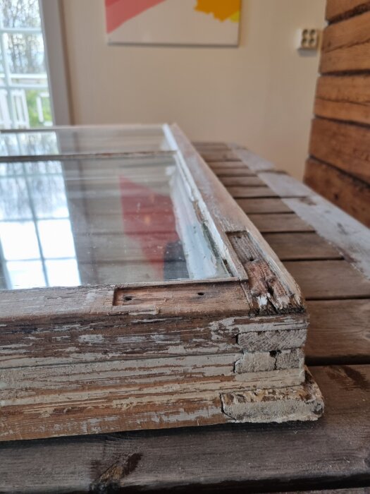 Gammalt fönstersnickeri med slitet trä och flagande färg på ett arbetsbord.