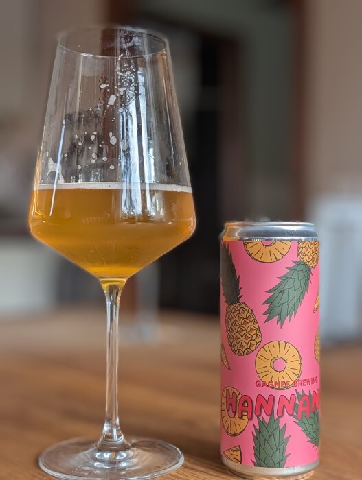 En glas med suröl och en färgglad burk med ananasgrafik från Gagnef Brewing på ett bord.