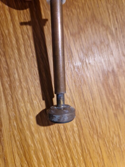 Stång med fastsatt kägla på ett brunt trägolv, för diskussion om att ta bort käglan med polygrip.