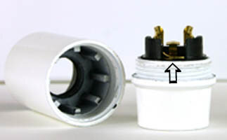 E27 lamphållare isärskruvad med mässingsgördel synlig, pil pekar mot bleck som låser den övre delen.