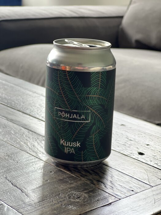Pöjala Kuusk IPA i en metallburk med granmönster, placerad på ett träbord.