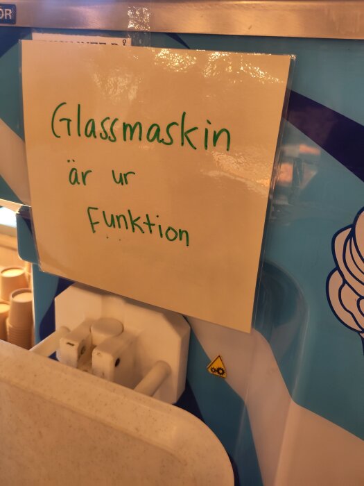Glassmaskin med skylt där det står "Glassmaskin är ur funktion" i grönt.