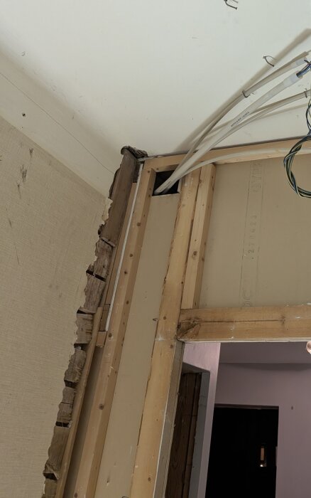 Väggkonstruktion från 1919, delvis exponerad med träreglar, gipsplatta och kablar i hörn; strukturen visas med öppningar och gamla plankor.