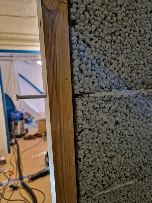 Hål i dörrkarmen med skruv mot vägg av lecablock i ett renoveringsprojekt.