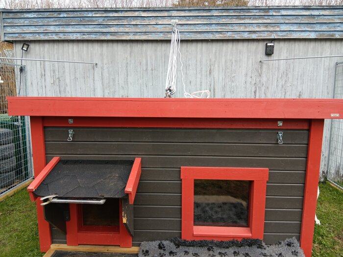 Block från Jula monterat på ett litet hus med rött och brunt trä, lina synlig för att lyfta taket.