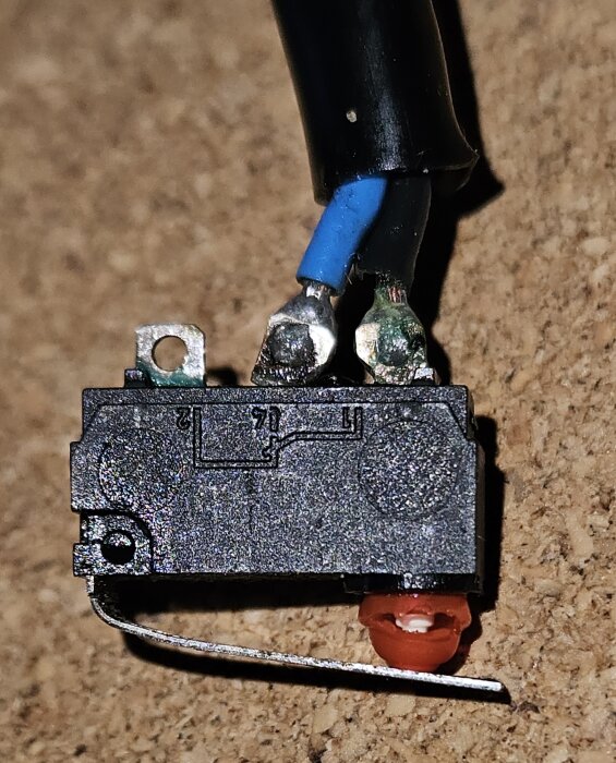 Brytare till huvlås på Volvo V70 D5 2008, med kablar anslutna. Detaljerad närbild på komponenten som diskuterats i forumet.