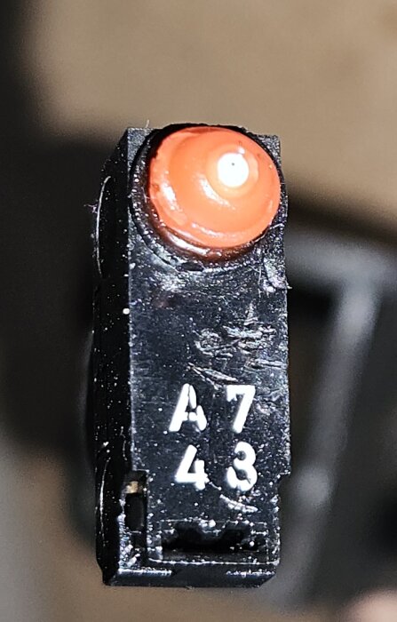 Närbild på en svart elektrisk brytare med en röd topp från V70 D5 2008, markerad med A743.