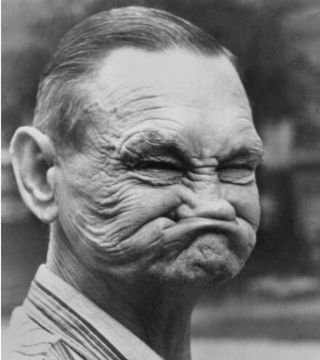 Äldre man med ansiktet sammantryckt i en rolig min, svartvitt foto.